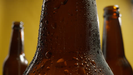 Nahaufnahme-Von-Kondensationstropfen-Auf-Flaschen-Mit-Kaltem-Bier-Oder-Alkoholfreien-Getränken-Vor-Gelbem-Hintergrund